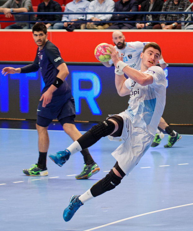 Eine Gruppe von Männern spielt Hallenhandball auf einem Court während des Futsal-Weltmeisterschaft 2019, mit Zuschauern im Hintergrund und einer Anzeigetafel mit den Spieltagen.