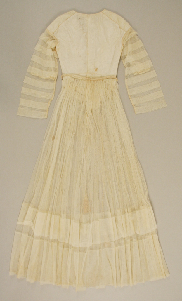 Ein weißes, langärmeliges Kleid mit einer gerafften, bodenlangen Schleppe auf einer weißen Oberfläche, das eine hohe Taille, voluminösen Stoff und einen dezenten Schimmer aufweist.