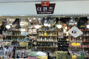 Ein unordentlicher Laden in Seoul mit verschiedenen Artikeln wie Körben, Lampen, Flaschen und Spielzeugen auf Regalen, mit einer Tafel oben, die darauf hinweist, dass es einer der besten koreanischen Läden ist.