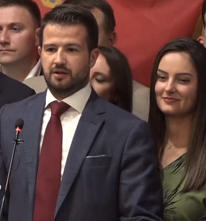 Ein Mann im Anzug spricht an einem Pult mit einem Mikrofon zu einer Menge hinter einem Banner, wahrscheinlich über ein gouvernementales Verbot von sozialen Medien.