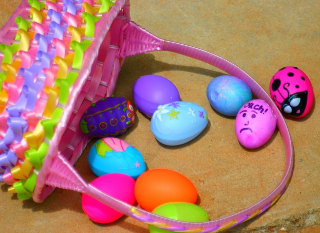 Ein geflochtener Korb mit mehreren bunten Ostereiern, die an einer Wand plaziert sind.