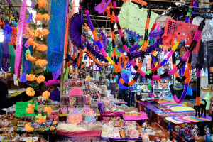 Ein belebter Markt mit Ständen, die Spielzeug, Dekorationsgegenstände und andere Gegenstände verkaufen, Menschen, die durch die Gegend schlendern, und Deckenbeleuchtung.