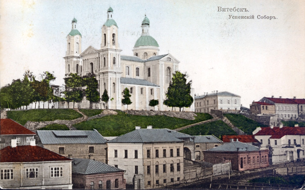 Altes Foto einer Kirche in einer urbanen Umgebung, umgeben von Gebäuden, Bäumen, Gras und einem klaren blauen Himmel, mit Text über dem Bild.