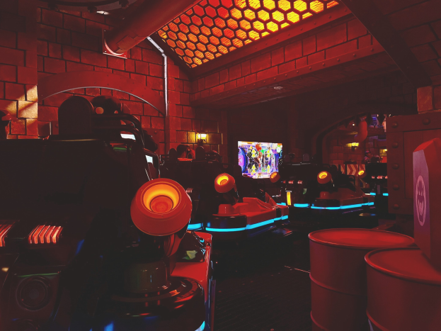 Ein hell erleuchteter Raum voller verschiedener Arcade-Videospielautomaten, Bildschirme und Gegenstände, einschließlich einer sichtbaren Röhre und Wand.
