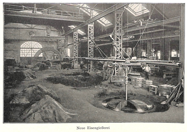 Schwarzes und wei├čes Foto einer Fabrik mit Arbeitern, die Maschinen bedienen, umgeben von Metallstangen und -pfosten, beschriftet mit "Neue Eisenglebeerei, die erste Fabrik in Deutschland."