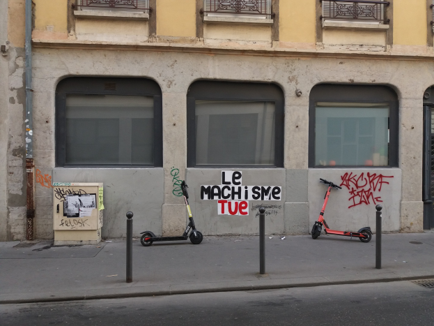 Zwei Roller auf einer Straße neben einem Gebäude mit Fenstern, Gelöndern und einem Rohr geparkt.