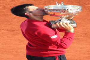 Novak Djokovic hält den French Open-Pokal nach seinem Sieg gegen Rafael Nadal im Finale der Herren-Einzel hoch und feiert mit einem triumphalen Gesichtsausdruck.
