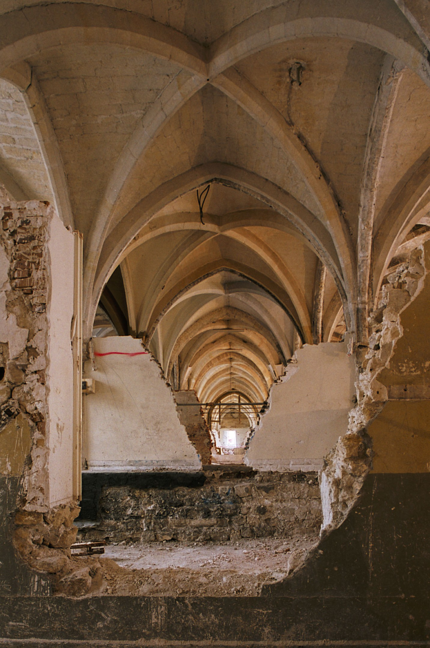 Ein altes Gebäude mit Gewölbedachung und einer gebrochenen Wand, das Zeichen von Verfall und historischer Pracht zeigt.