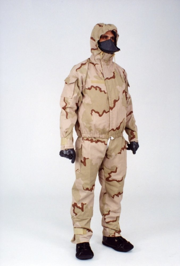 Ein Mann in einem Tarnmuster-Schutzoverall mit Kapuze und Maske steht vor einem weißen Hintergrund.