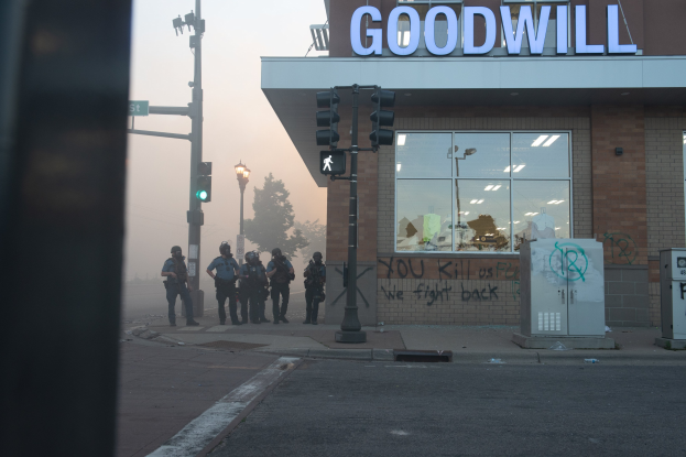 Polizisten in Helmen und taktischer Ausrüstung stehen vor einem Second-Hand-Laden, bewaffnet.
