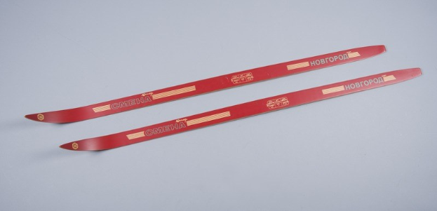 Zwei rote Skier gestapelt auf einer weißen Oberfläche mit Text, der die Marke oder Art anzeigt.