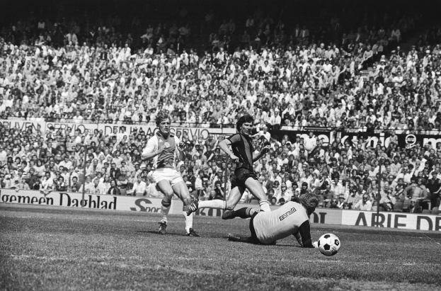 Schwarzes und weißes Foto von Männern, die auf einem Feld Füßball spielen, mit Zuschauern im Hintergrund und einer Bundesliga 1978-79 Ajax 1-1 Hannover 96-Tafel.