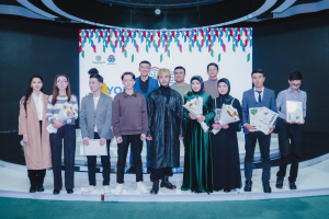 Gruppe von Menschen auf einer Bühne mit Blumensträußen und Urkunden, im Hintergrund ein "Jugend-Solar-Preis 2019"-Plakat.