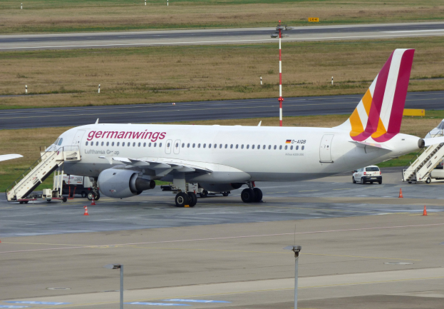 Germanwings Airbus A320-200 am Frankfurter Flughafen geparkt mit Bodenfahrzeugen, Verkehrskegeln, Pfählen und Gras im Hintergrund.