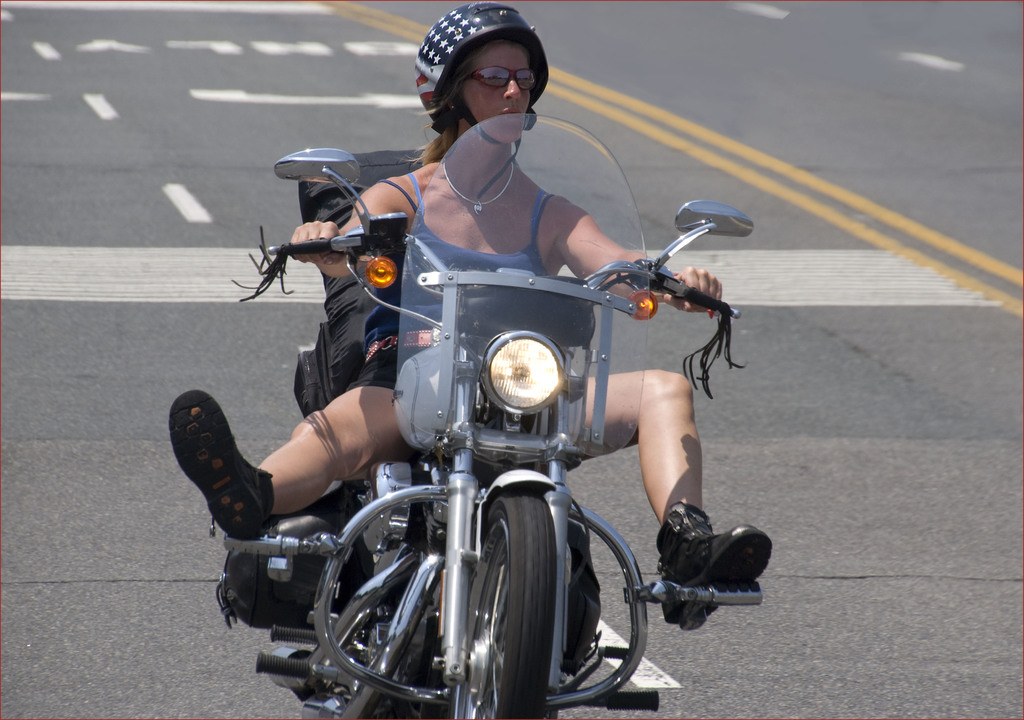 Eine Frau mit einem schwarzen Helm fährt auf der Straße mit dem Fahrrad.