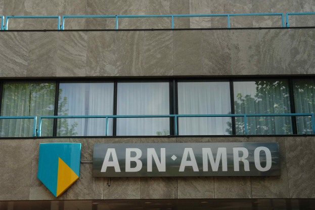 Außenansicht eines ABN AMRO-Gebäudes mit einer Tafel, einer Plakette, die es als Hauptsitz angibt, einem Geländer und Vorhangglasfenstern.