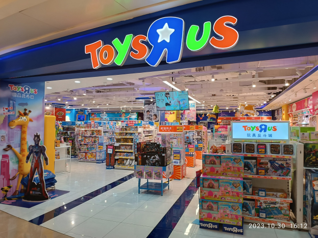 Ein Toys R Us-Laden in einem Einkaufszentrum mit Regalen voller Spielzeuge, einem sichtbaren Namensschild, Deckenleuchten und einem Wasserzeichen in der rechten unteren Ecke.
