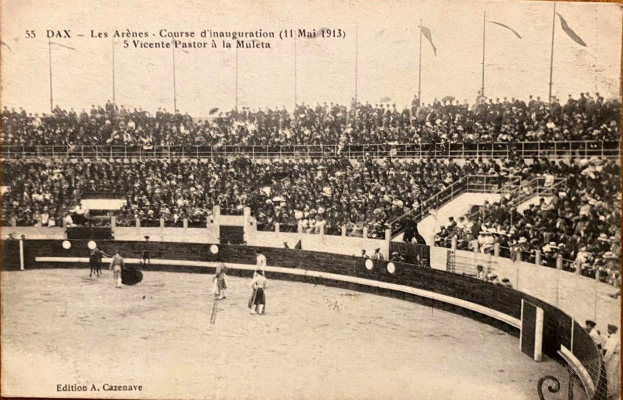 Schwarzes und weißes Foto eines Boxkampfes in einem Stadion mit Zuschauern auf den Rängen und einer Gruppe von Menschen in der Mitte des Ringbereichs.