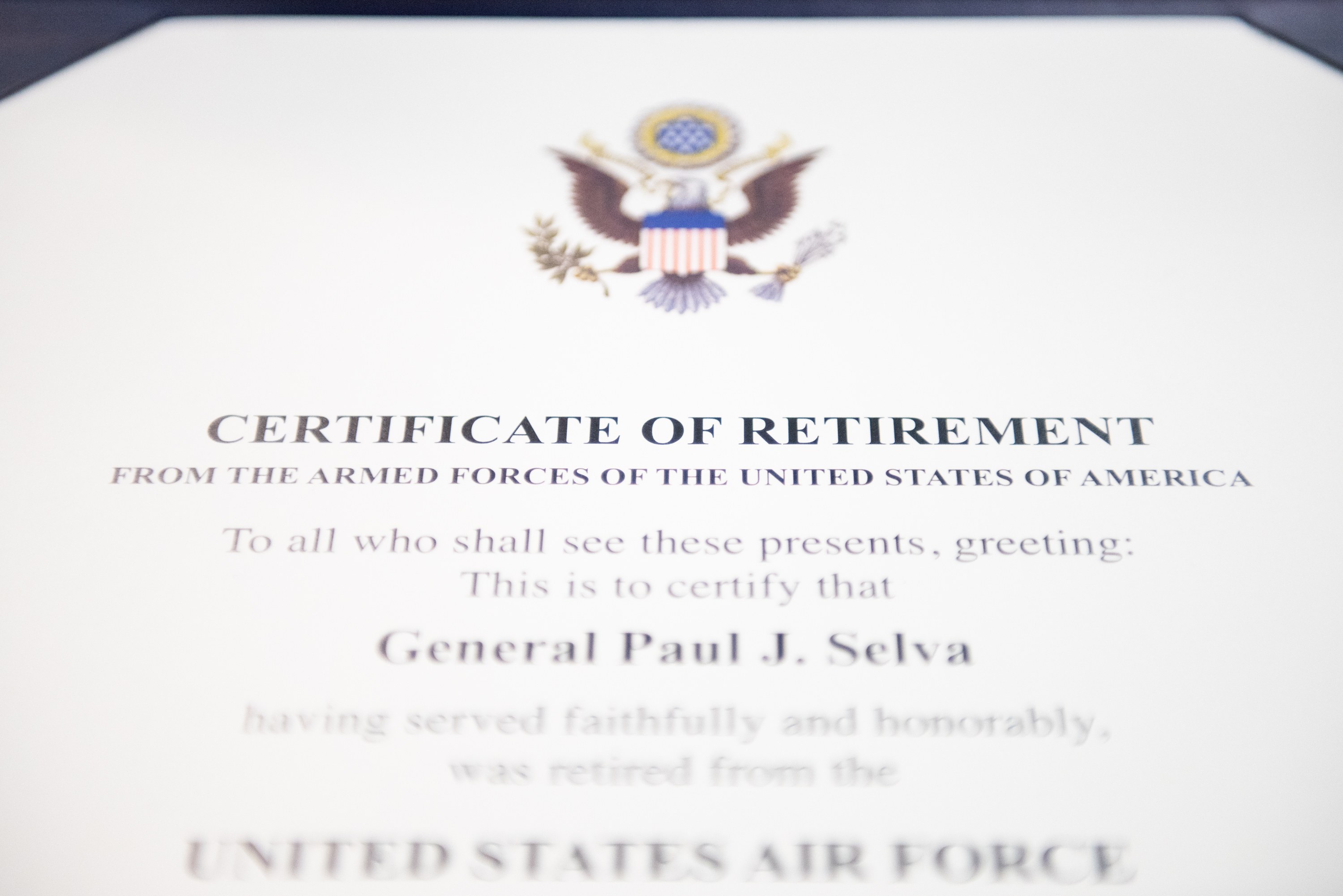 Rahmenurkunde für den Ruhestand von der United States Air Force mit blauem Rand, die ein Schild-Logo mit einem zentralen Stern, einem Lorbeerkranz und einer schwarzen 'Ruhestand'-Bannerschrift zeigt.